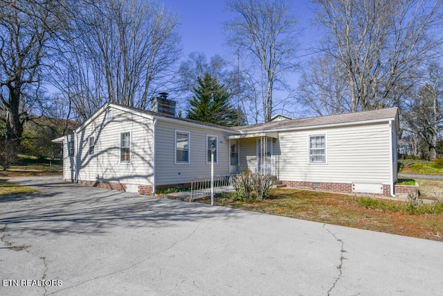 view of front of property featuring aphalt driveway, crawl space, and a chimney