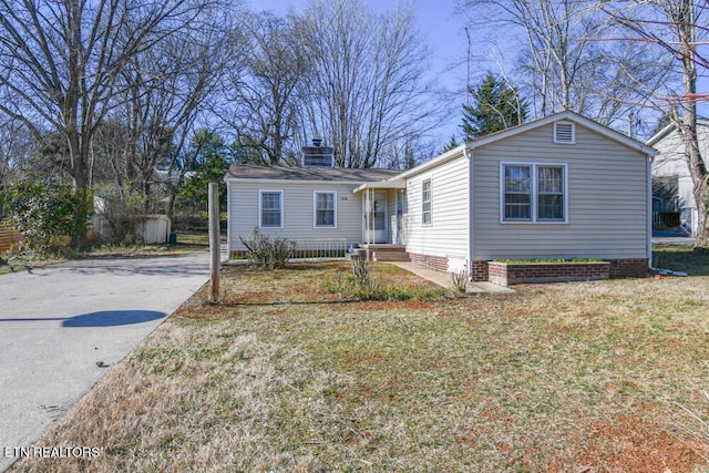 view of front facade with driveway, a chimney, and a front yard