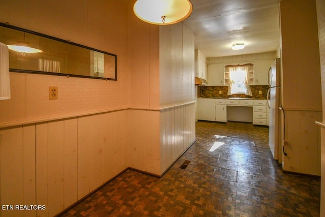 hall featuring a wainscoted wall, wooden walls, and visible vents