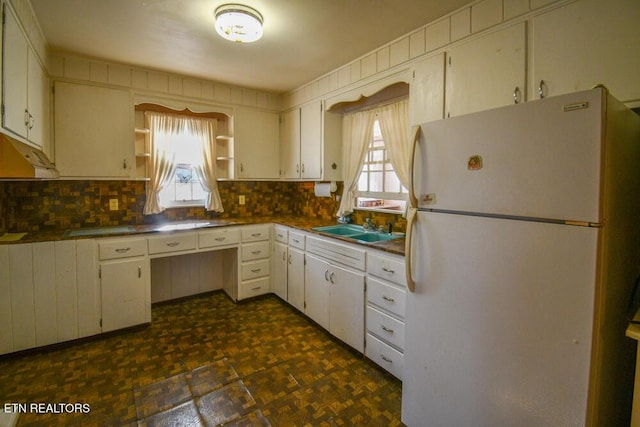 kitchen featuring tasteful backsplash, open shelves, a sink, and freestanding refrigerator