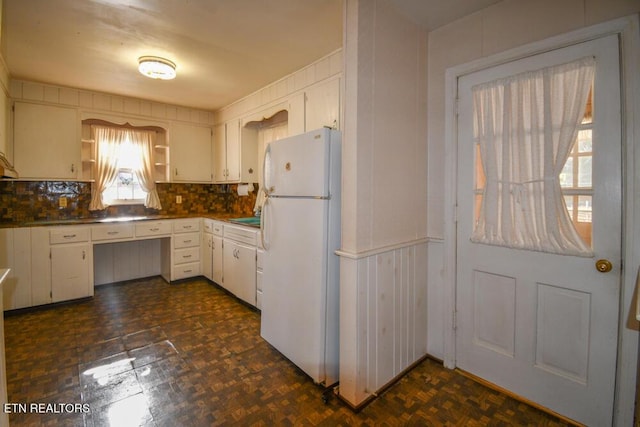 kitchen with open shelves, dark countertops, backsplash, freestanding refrigerator, and white cabinetry