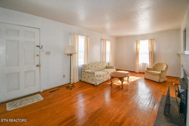 unfurnished living room featuring visible vents, a glass covered fireplace, light wood-style flooring, and baseboards