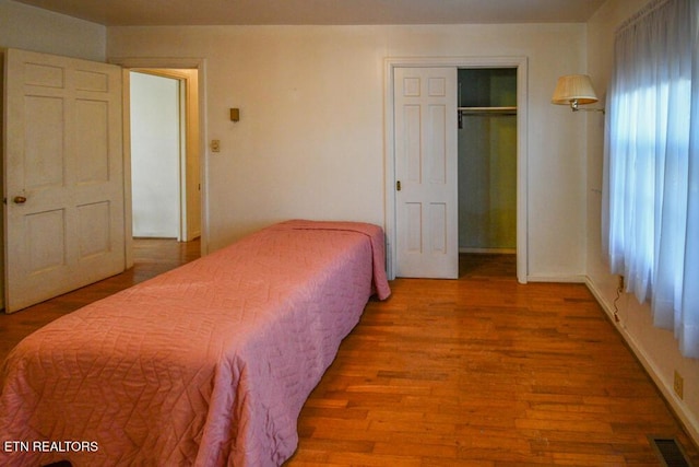 bedroom featuring baseboards, a closet, visible vents, and wood finished floors