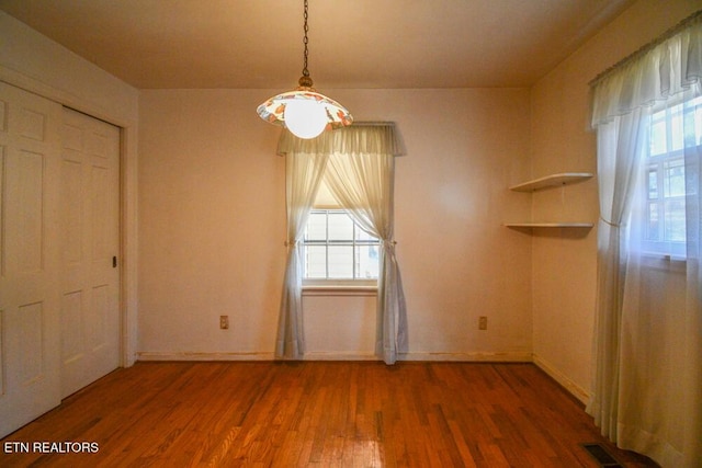 unfurnished dining area featuring visible vents, baseboards, and wood finished floors