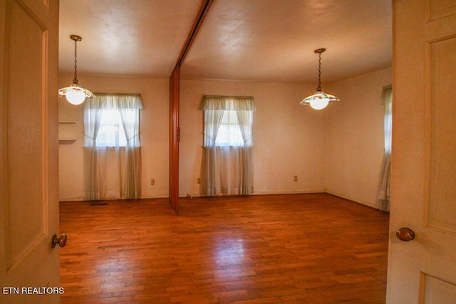 spare room with plenty of natural light and wood finished floors