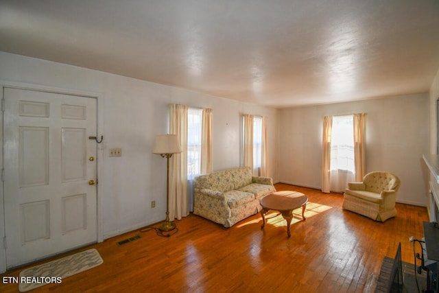 living area featuring a wealth of natural light, visible vents, and hardwood / wood-style flooring