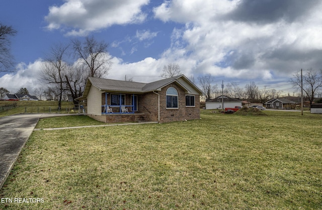 view of front of property featuring crawl space, fence, a front lawn, metal roof, and brick siding