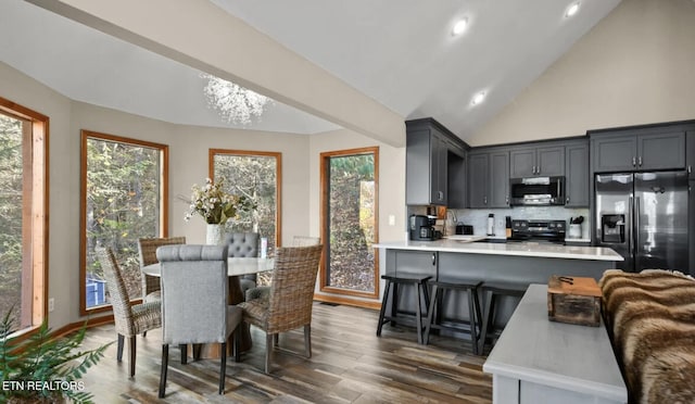 3809 Ravens Den Way, Sevierville, TN 37862 - kitchen with dark wood-style flooring, a peninsula, stainless steel appliances, light countertops, and a kitchen bar