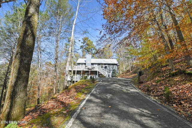 view of front facade featuring a garage, stairs, a chimney, and aphalt driveway