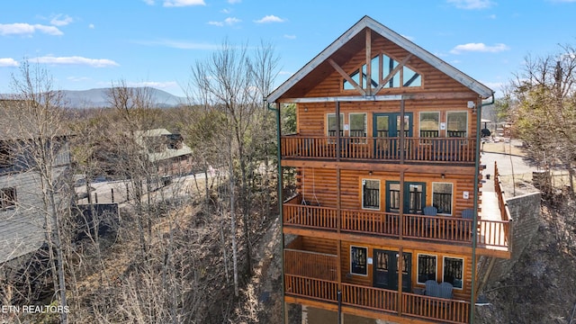 view of front of property featuring french doors, log veneer siding, a mountain view, and a balcony