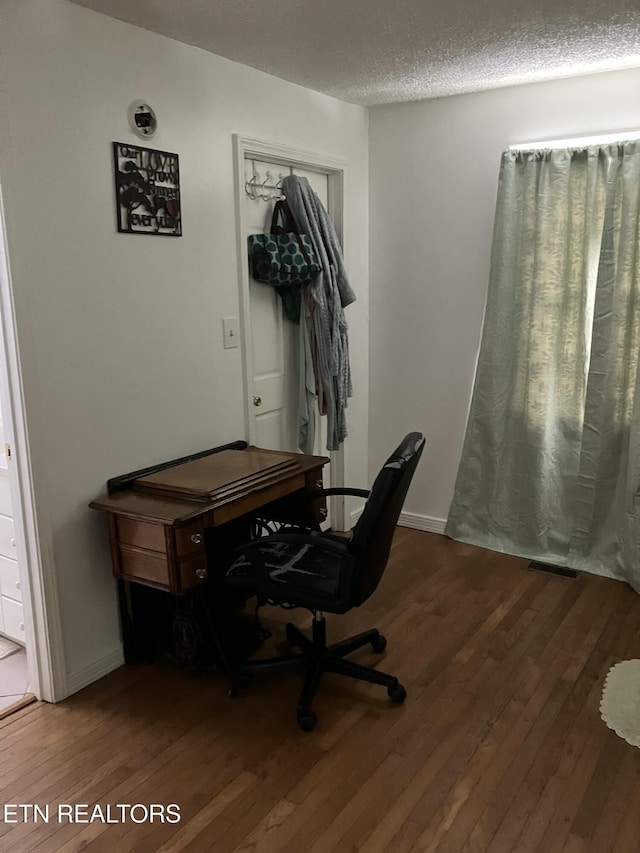 office area with a textured ceiling, dark wood finished floors, and baseboards