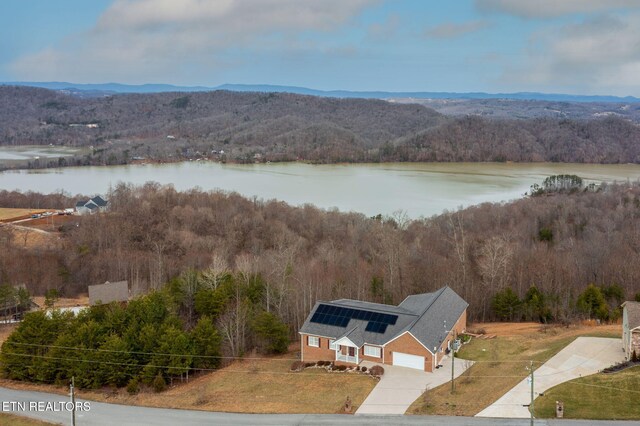 aerial view with a water and mountain view and a view of trees