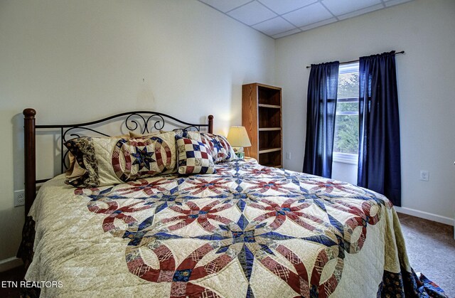 carpeted bedroom featuring baseboards and a drop ceiling