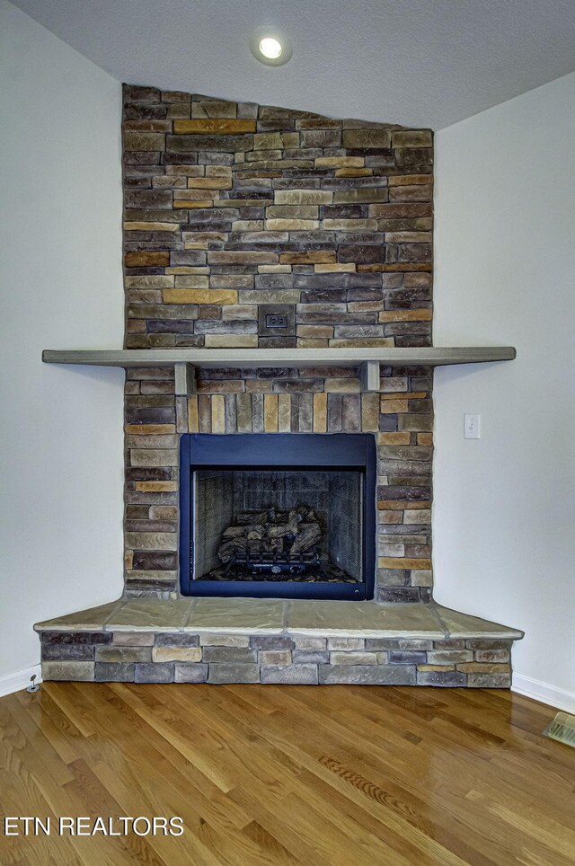 interior details featuring visible vents, a fireplace, baseboards, and wood finished floors