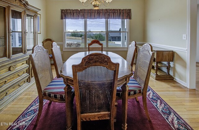 dining space featuring a notable chandelier, baseboards, and wood finished floors