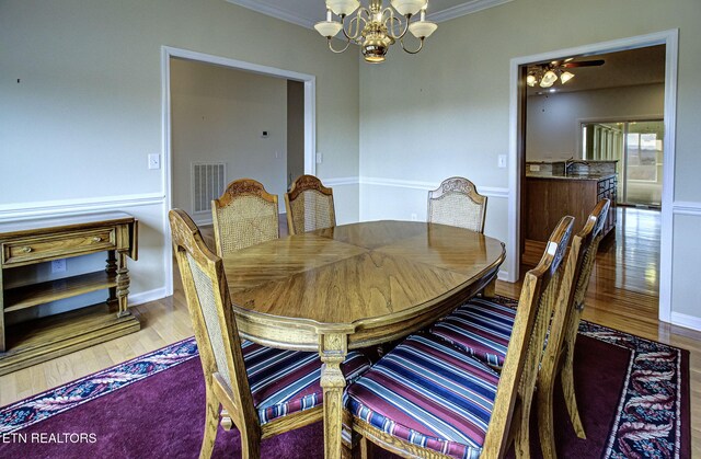 dining room with crown molding, a notable chandelier, visible vents, wood finished floors, and baseboards