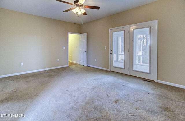 spare room featuring light colored carpet, visible vents, and baseboards