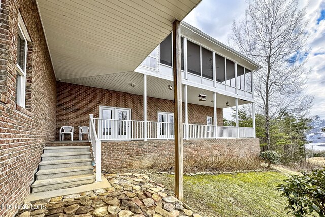 view of side of home with a sunroom, french doors, and brick siding