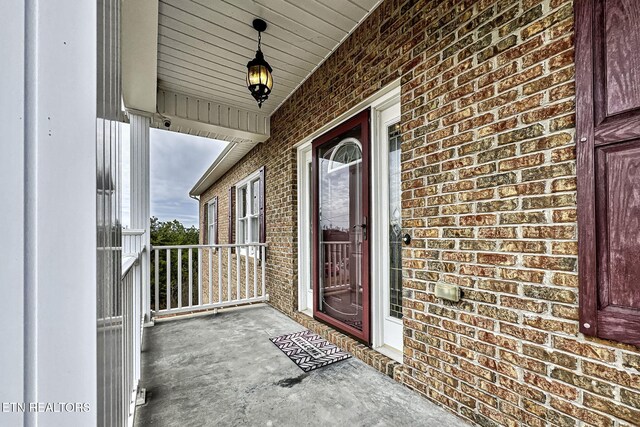 view of exterior entry featuring covered porch and brick siding