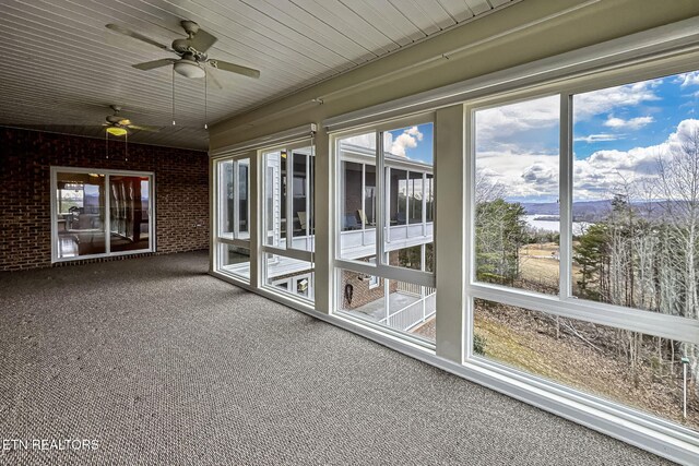 unfurnished sunroom with wood ceiling and a ceiling fan