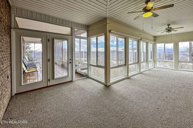 unfurnished sunroom featuring wooden ceiling, plenty of natural light, and ceiling fan