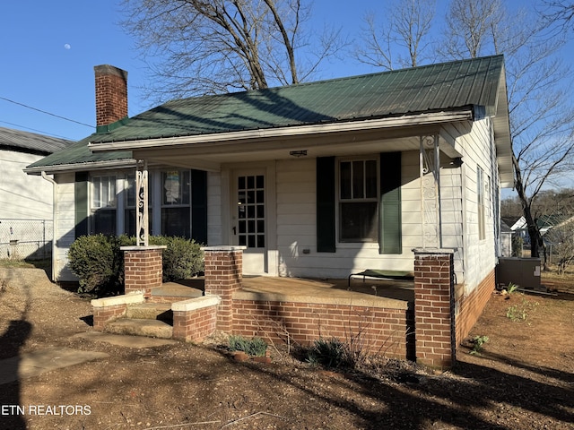 view of front of home with a chimney, covered porch, and metal roof