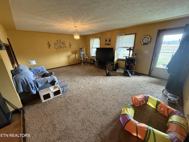 carpeted living area featuring a notable chandelier, a textured ceiling, and baseboards