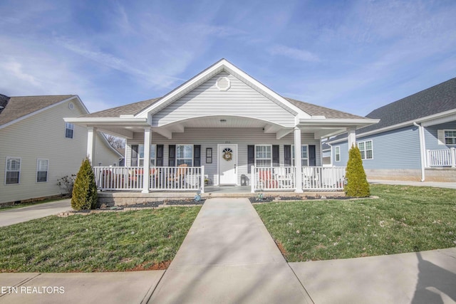 view of front of home with covered porch, a shingled roof, and a front yard