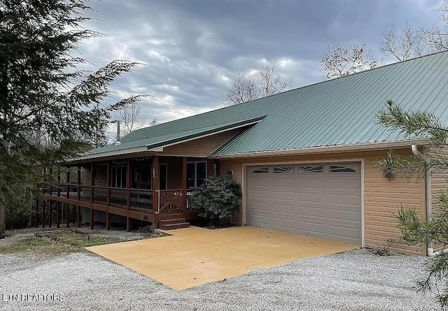 view of front of home with a garage, covered porch, metal roof, and gravel driveway