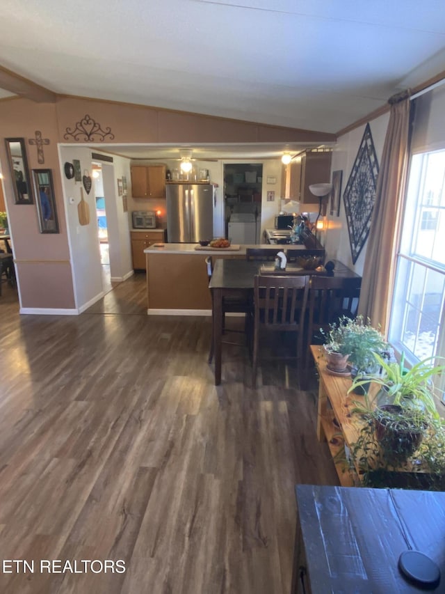 dining area with dark wood-style floors, vaulted ceiling, and baseboards