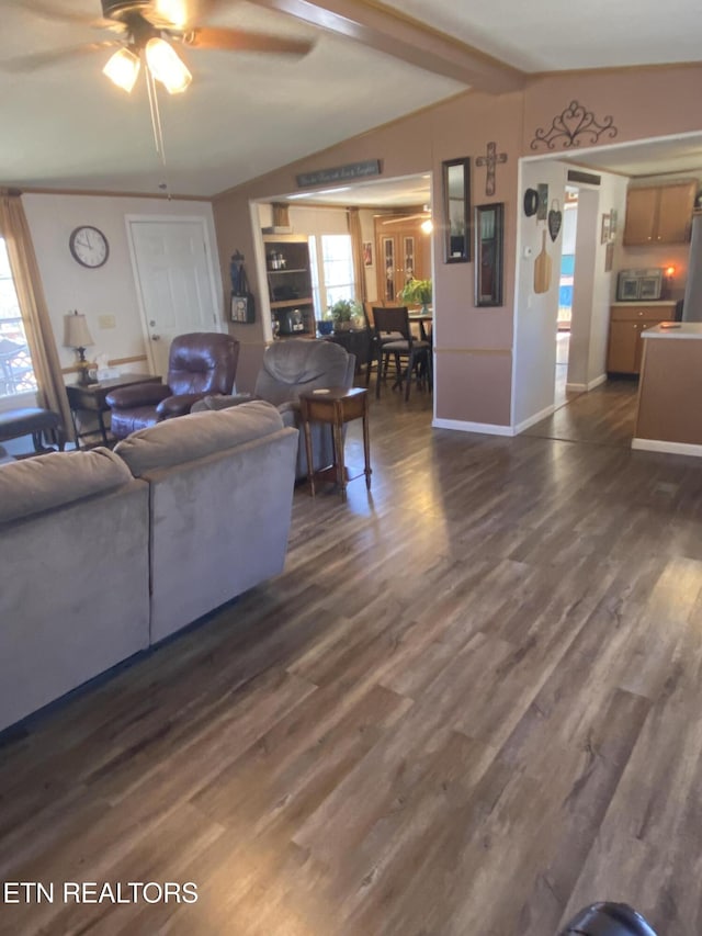 living room featuring dark wood finished floors, a healthy amount of sunlight, and vaulted ceiling with beams