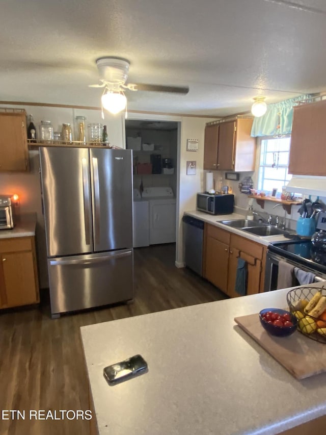 kitchen featuring a sink, appliances with stainless steel finishes, light countertops, and washer and dryer