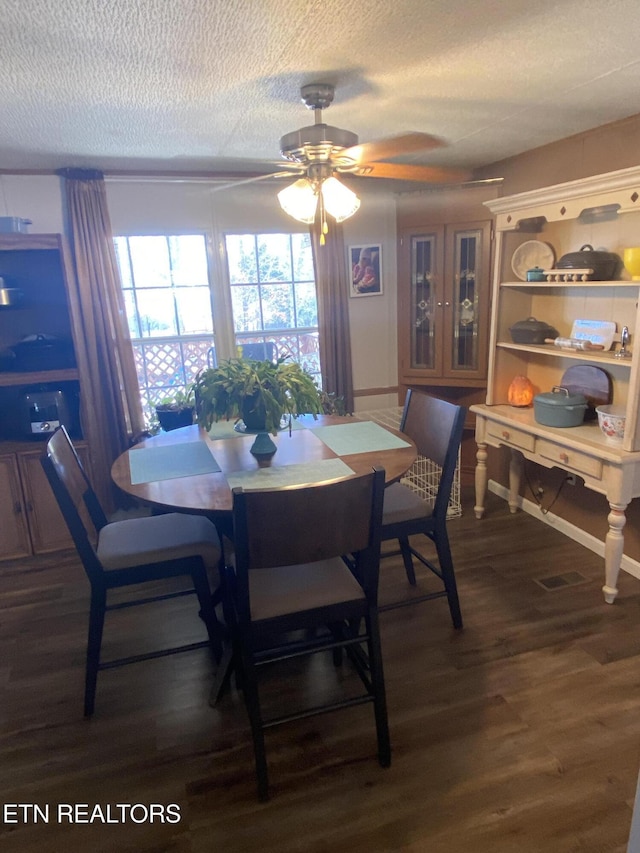 dining room with a textured ceiling, a ceiling fan, and dark wood-type flooring