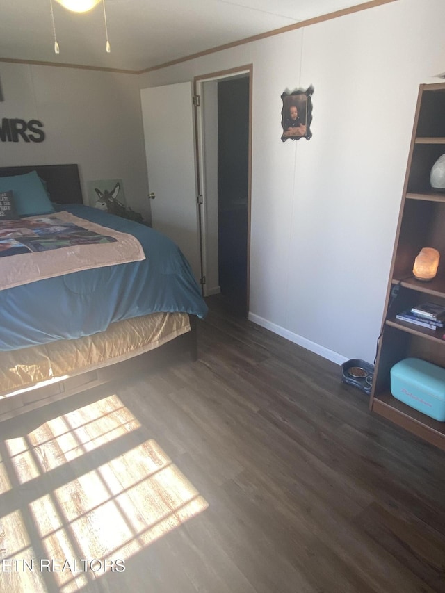 bedroom featuring ornamental molding, wood finished floors, and baseboards