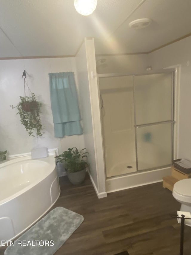 bathroom with toilet, a stall shower, and wood finished floors