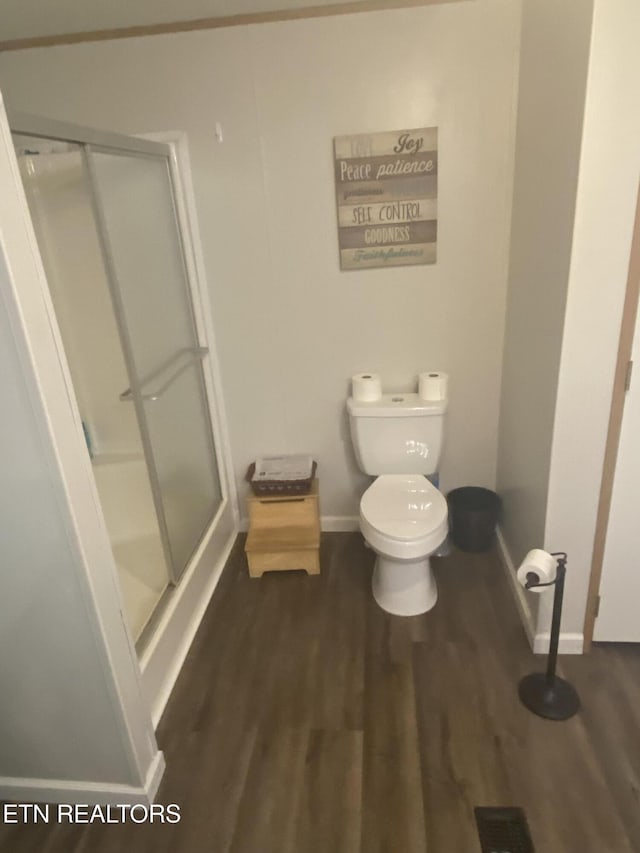 full bath featuring a stall shower, wood finished floors, toilet, and baseboards