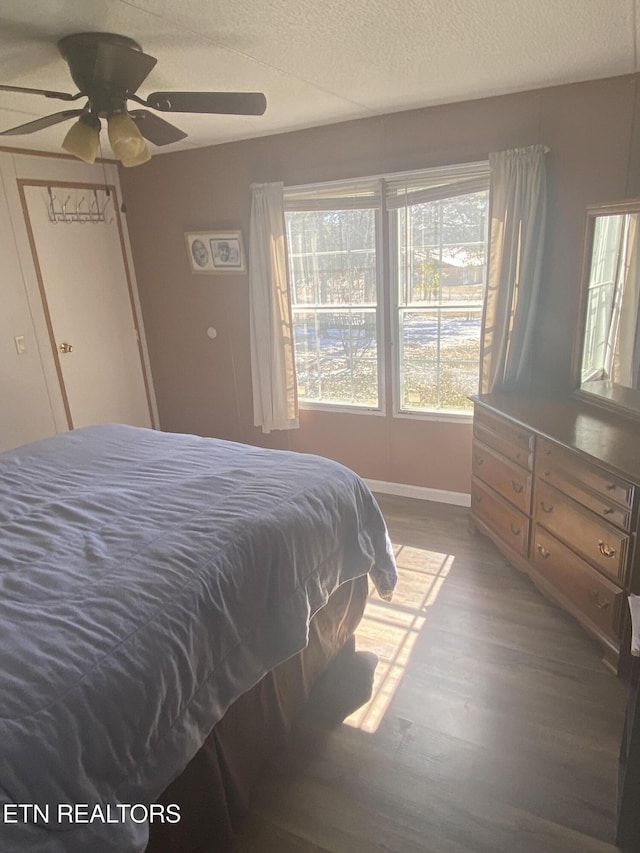 bedroom featuring a ceiling fan, a textured ceiling, baseboards, and wood finished floors