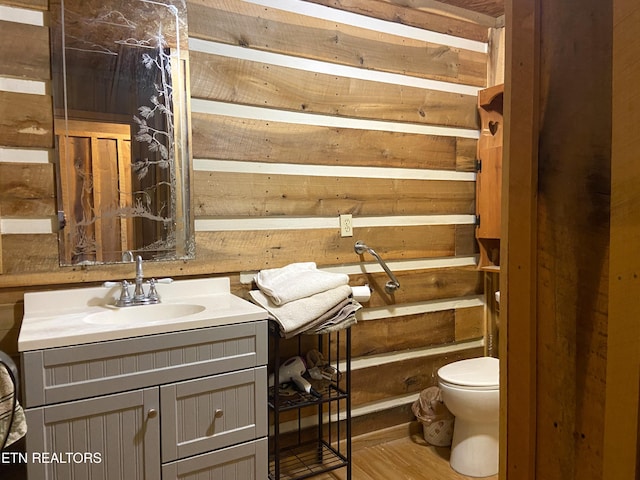 bathroom with wood finished floors, a sink, toilet, and wooden walls