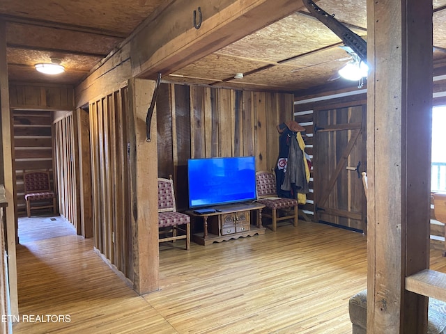 basement featuring light wood-type flooring and wood walls