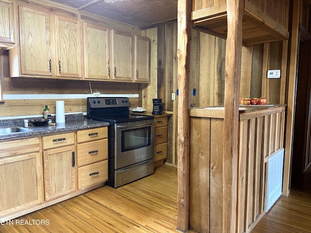 kitchen featuring electric stove, light brown cabinets, wooden walls, and light wood finished floors