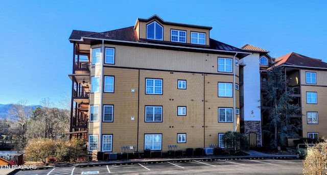 view of building exterior with uncovered parking and central AC