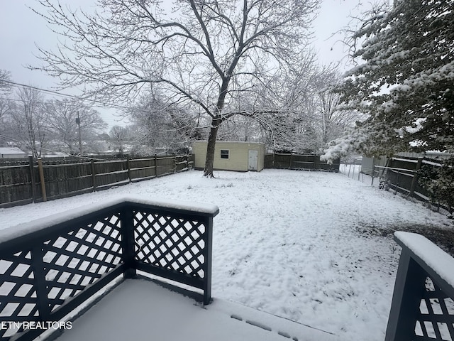 snowy yard featuring a fenced backyard, an outdoor structure, and a shed