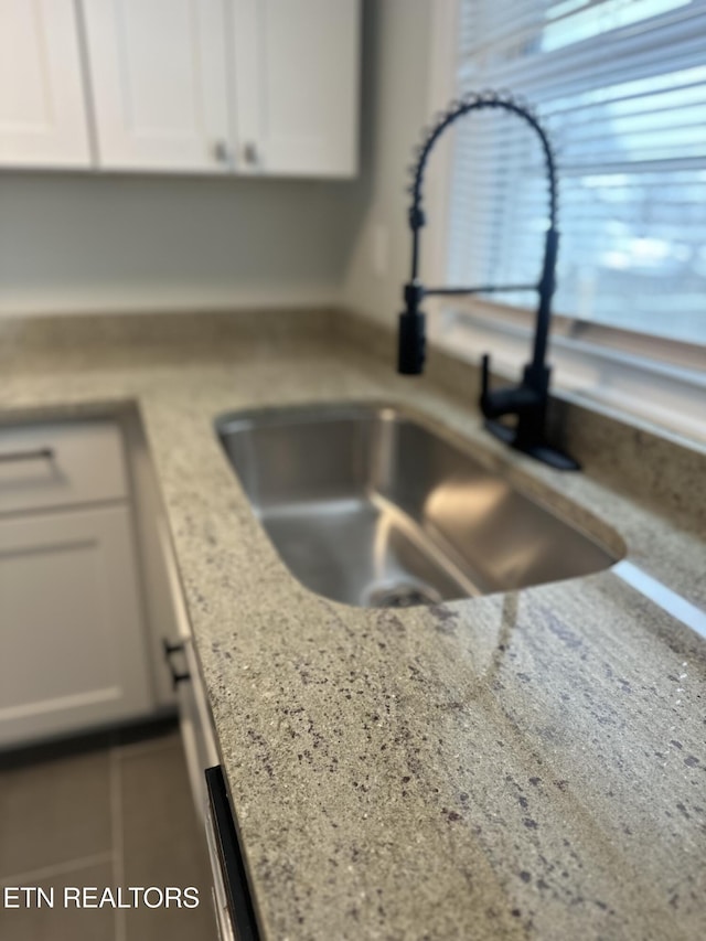 details with light stone counters, white cabinets, and a sink