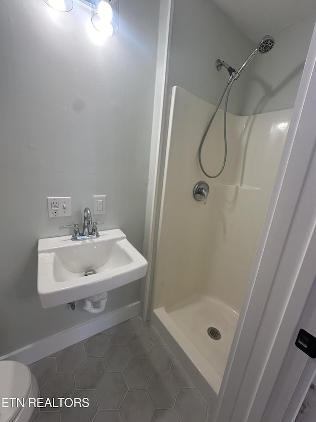 bathroom with a stall shower, tile patterned flooring, a sink, and toilet