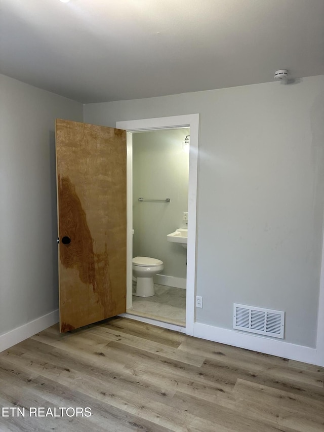 bathroom featuring toilet, baseboards, visible vents, and wood finished floors