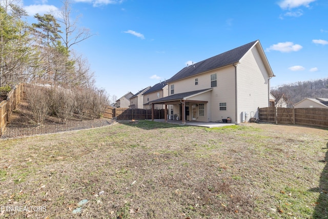 rear view of property featuring a yard, a patio area, and a fenced backyard