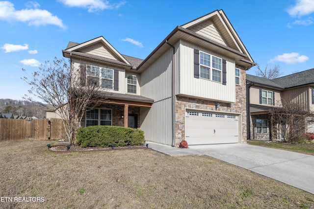 traditional home featuring an attached garage, fence, stone siding, concrete driveway, and a front yard