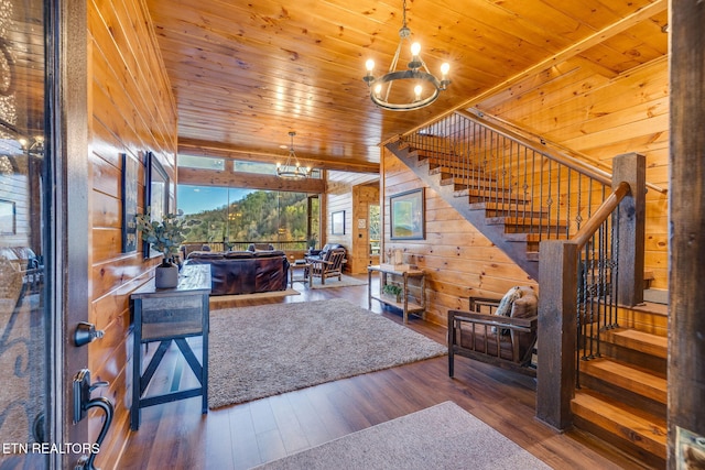 living area featuring wooden walls, a notable chandelier, wood finished floors, wood ceiling, and stairs