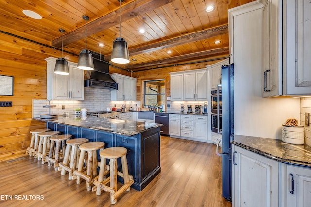 kitchen featuring a kitchen breakfast bar, stainless steel dishwasher, custom exhaust hood, decorative backsplash, and light wood finished floors