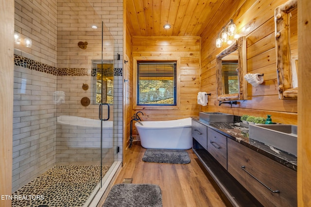 full bathroom with a freestanding tub, wood finished floors, a sink, double vanity, and a stall shower